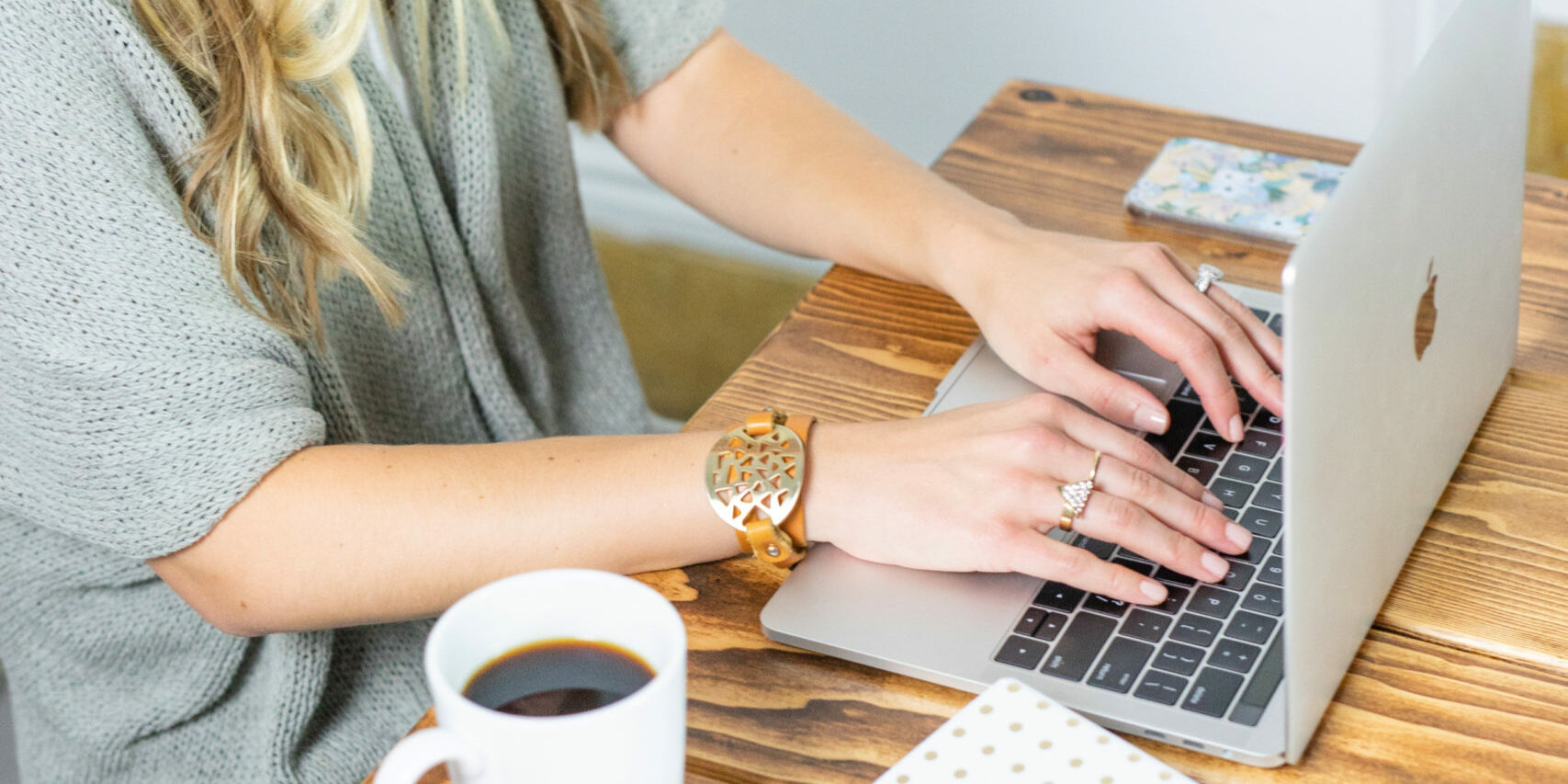 woman typing on computer for seach results with cofee and papers on desk